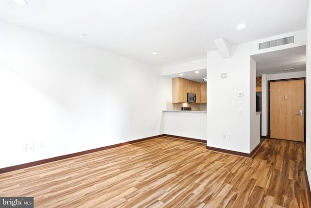 unfurnished living room with recessed lighting, light wood-type flooring, visible vents, and baseboards