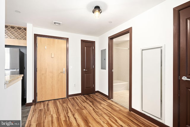 interior space featuring light wood-type flooring, visible vents, electric panel, and baseboards