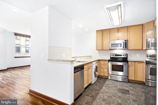 kitchen with appliances with stainless steel finishes, washer / clothes dryer, light brown cabinets, and a sink