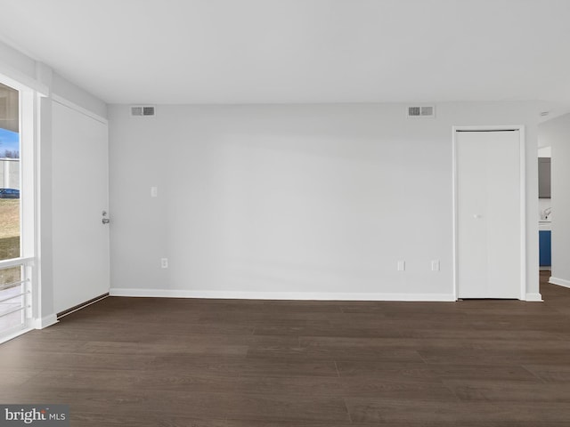 empty room with baseboards, visible vents, and dark wood-style flooring