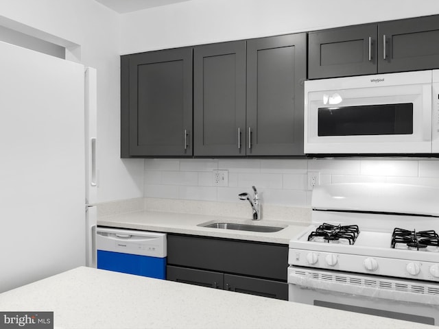 kitchen with gray cabinets, white appliances, a sink, and backsplash