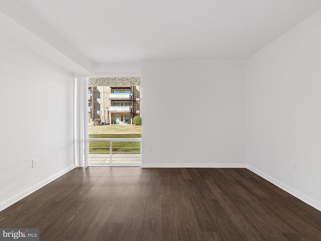 spare room with baseboards and wood finished floors