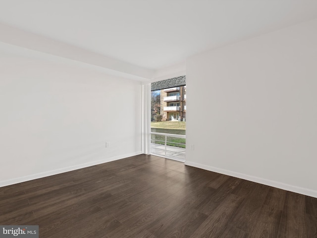 unfurnished room with dark wood finished floors and baseboards