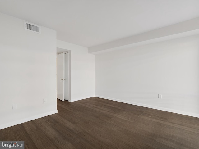 unfurnished room with dark wood-type flooring, visible vents, and baseboards