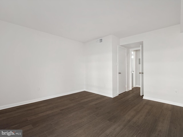 unfurnished room featuring baseboards, visible vents, and dark wood-type flooring