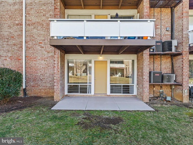 property entrance featuring central AC, brick siding, a patio, and a balcony