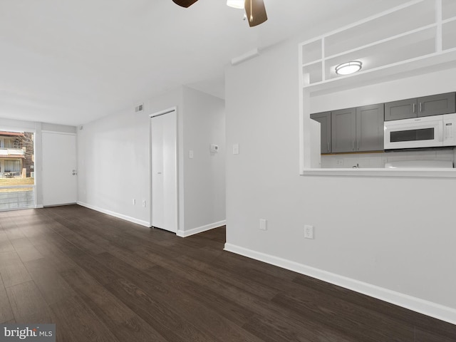 unfurnished living room with ceiling fan, dark wood-style flooring, and baseboards