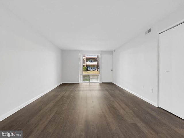 interior space featuring dark wood-style flooring, visible vents, and baseboards