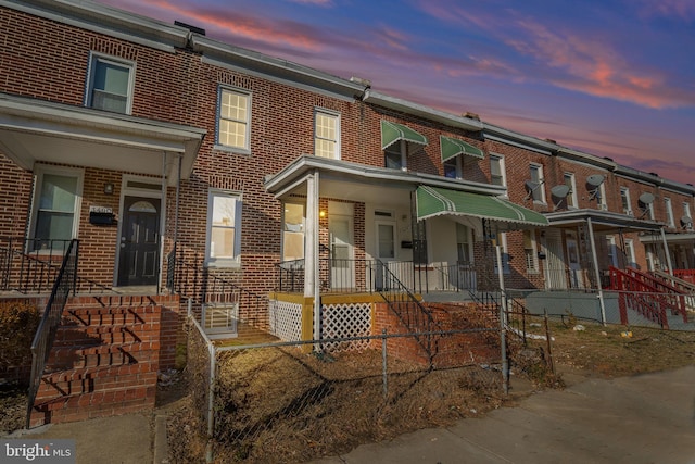 multi unit property featuring brick siding and a fenced front yard