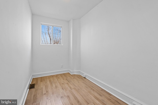 spare room featuring light wood-type flooring, visible vents, and baseboards