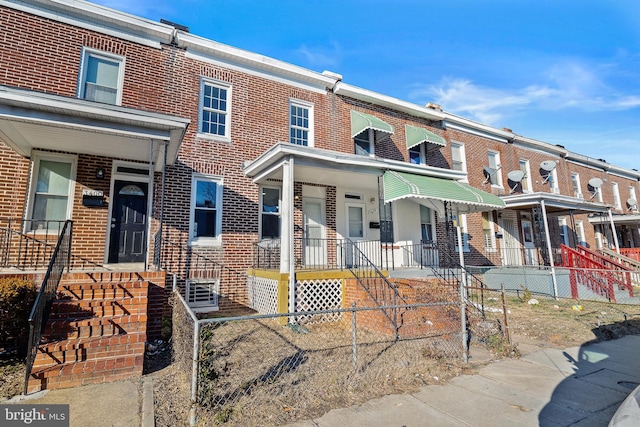 multi unit property featuring brick siding and a fenced front yard