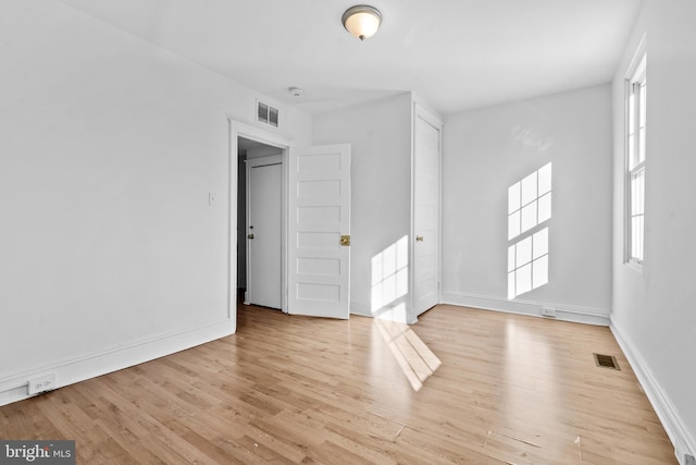 unfurnished room featuring wood finished floors, visible vents, and baseboards