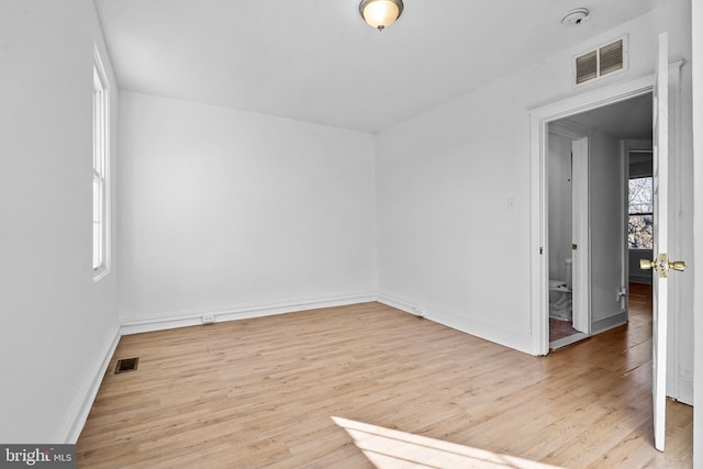 unfurnished room featuring plenty of natural light, visible vents, and wood finished floors