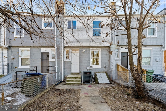 view of front of property featuring entry steps, central air condition unit, fence, and brick siding