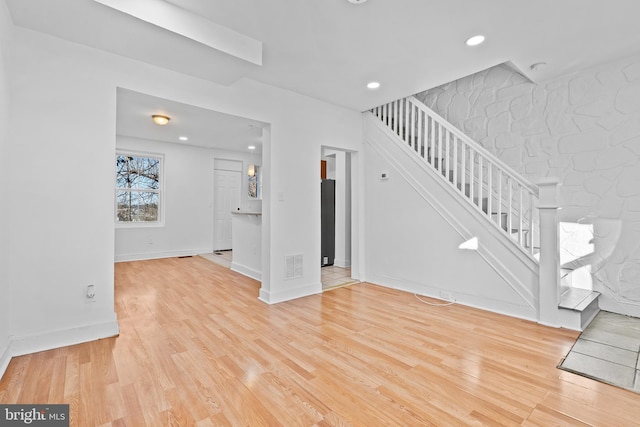 unfurnished living room with light wood-style floors, visible vents, stairway, and recessed lighting