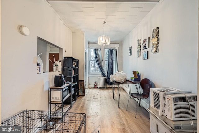 interior space with a notable chandelier, radiator heating unit, and light wood-style floors
