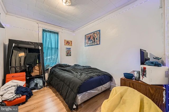 bedroom featuring ornamental molding and wood finished floors