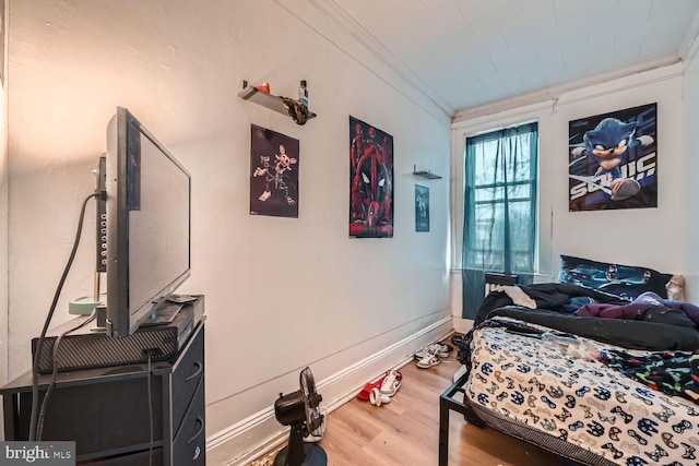 bedroom with crown molding, baseboards, and wood finished floors