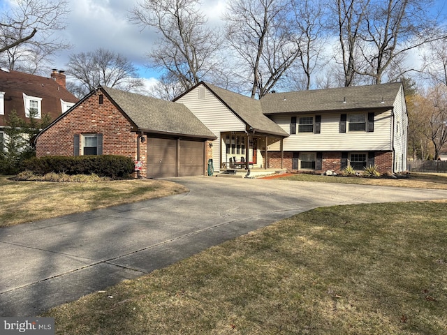 tri-level home with a garage, driveway, a front yard, and brick siding