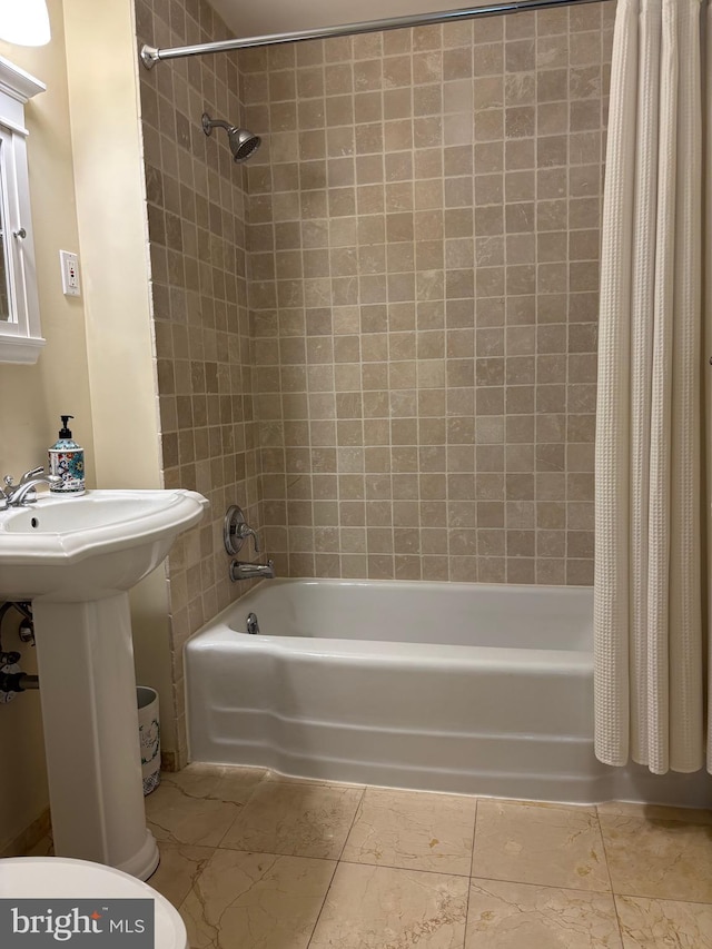 bathroom featuring toilet, shower / bath combo with shower curtain, and a sink