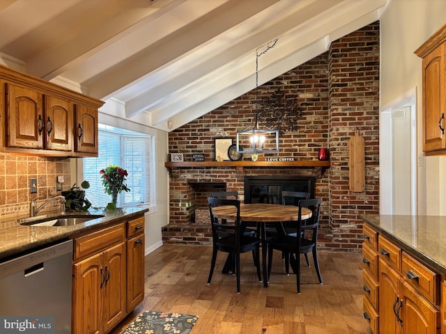 interior space featuring lofted ceiling with beams, brown cabinetry, a brick fireplace, a sink, and dishwasher