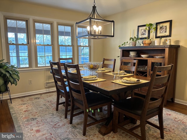 dining area with a healthy amount of sunlight, an inviting chandelier, baseboards, and wood finished floors