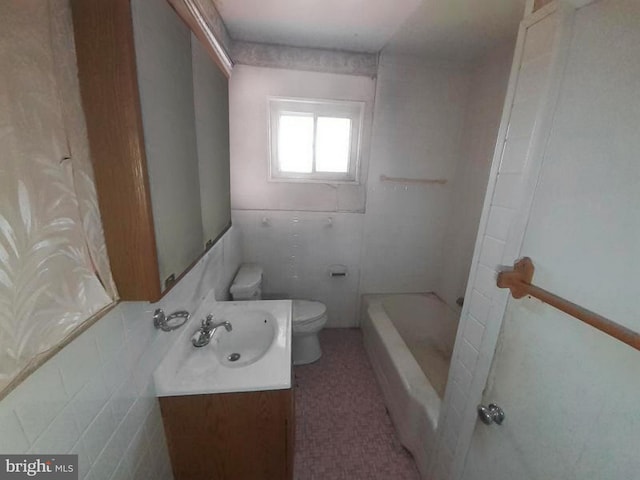 bathroom featuring toilet, a washtub, tile walls, and vanity