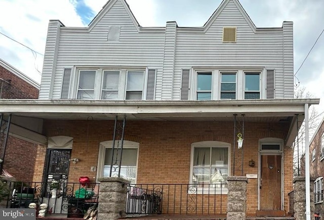 townhome / multi-family property with brick siding and covered porch