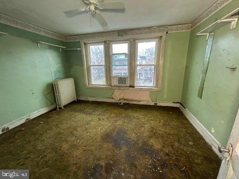 spare room featuring radiator, baseboards, and ceiling fan