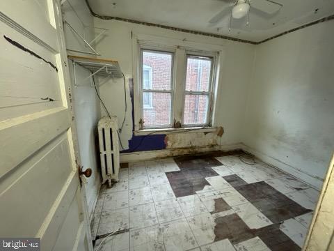 interior space featuring tile patterned floors, baseboards, radiator heating unit, and a ceiling fan