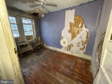 unfurnished room with a ceiling fan, radiator, and wood finished floors