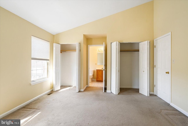 unfurnished bedroom with lofted ceiling, visible vents, light carpet, and baseboards