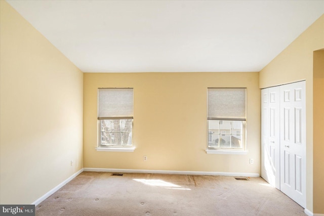 unfurnished bedroom with light carpet, baseboards, visible vents, and a closet