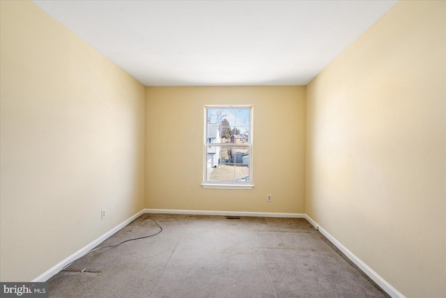 spare room featuring carpet and baseboards