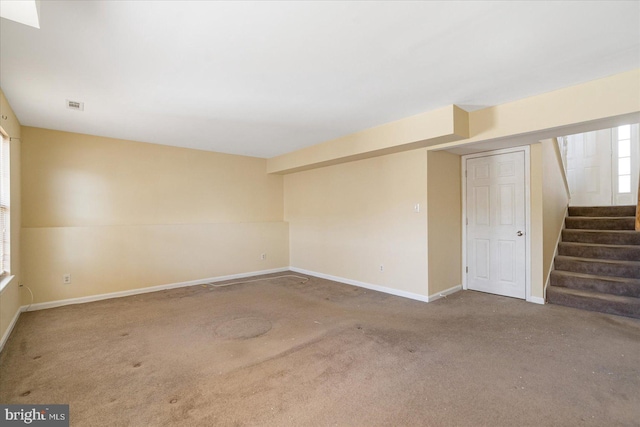 carpeted spare room featuring visible vents, stairway, and baseboards