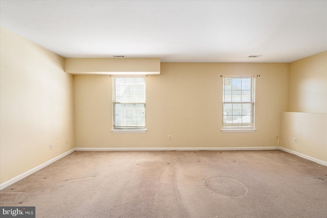 spare room featuring light carpet, visible vents, and baseboards