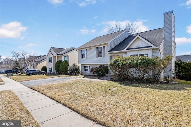 tri-level home with a residential view, a chimney, and a front lawn