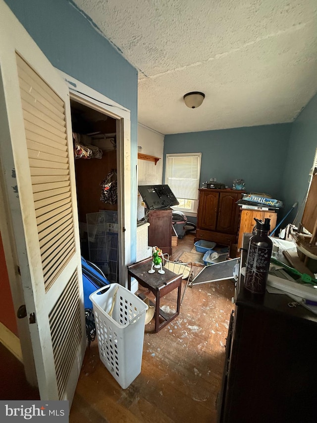 miscellaneous room with a textured ceiling and dark wood-type flooring