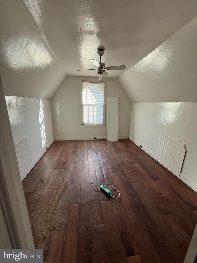 additional living space with vaulted ceiling, dark wood-style flooring, a textured ceiling, and baseboards