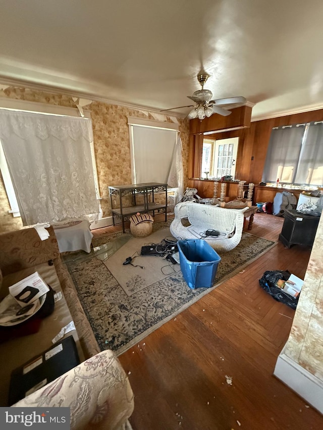 living area with a ceiling fan, wood finished floors, and ornamental molding