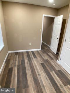 unfurnished bedroom featuring dark wood-style flooring and baseboards