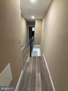 corridor featuring dark wood-style flooring and baseboards