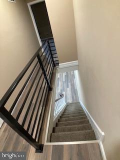 staircase featuring baseboards and wood finished floors