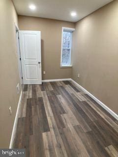 empty room featuring dark wood finished floors and baseboards