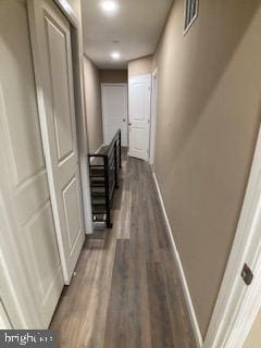 hall with visible vents, baseboards, and dark wood-style flooring