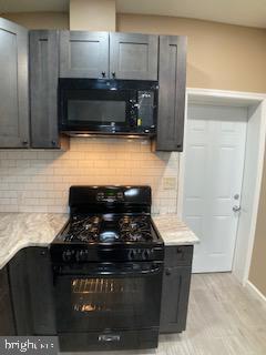 kitchen with tasteful backsplash, light countertops, and black appliances