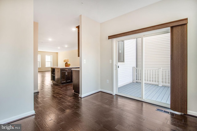 spare room featuring dark wood-style floors, visible vents, and baseboards