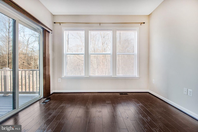 spare room featuring visible vents, baseboards, and dark wood finished floors