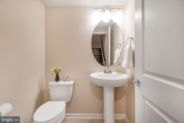 bathroom with toilet, baseboards, and a sink