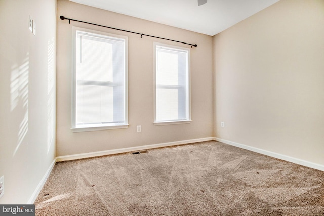 unfurnished room with carpet flooring, visible vents, and baseboards